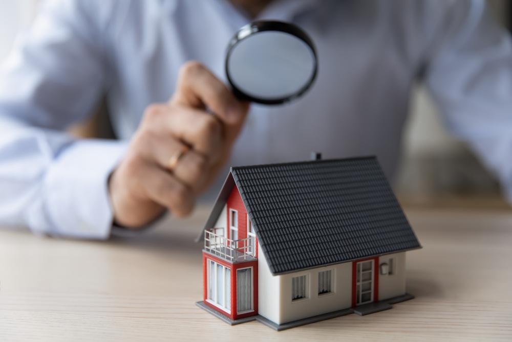 Real estate property appraisal inspection — magnifying glass over house model representing detailed property analysis in Queens NY