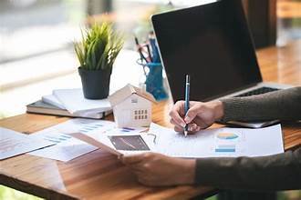 Real estate appraisal professional reviewing property documents and market data at a desk in Queens NY